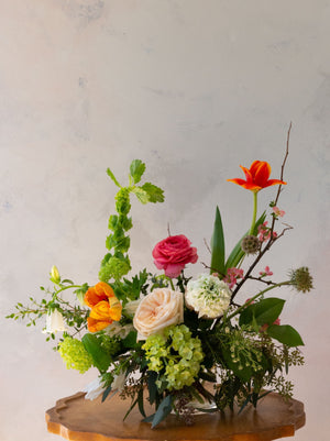 A floral design of ranunculus, garden roses, tulips, viburnum and bells of Ireland